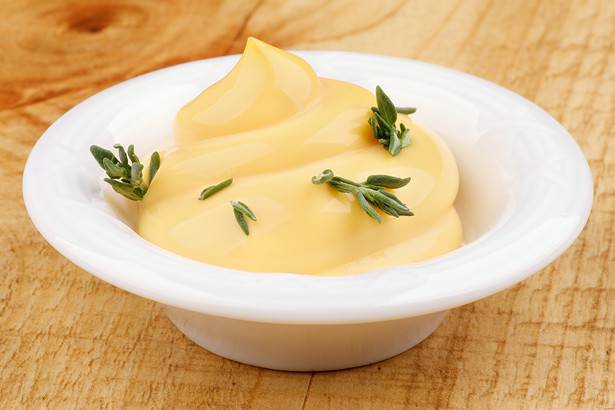 Mayonnaise Sauce Decorated with Thyme in White Bowl closeup on Rustic Wooden background