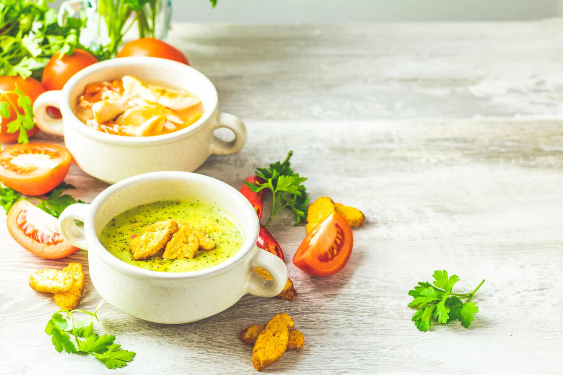 Home Icy 43 Delicious tomato and basil soups garnished with herbs, served in white bowls on a rustic wooden tabl.