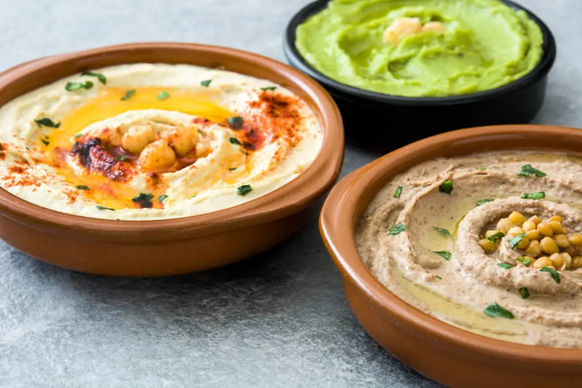 Hummus varieties served with fresh vegetables and pita chips for a healthy snack or appetizer.