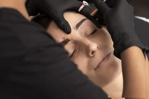 Woman receiving professional eyebrow microblading treatment at Icy Tales salon.