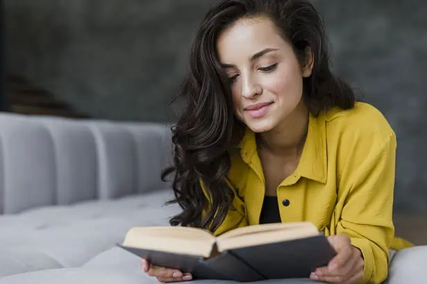 Woman reading a book in a cozy indoor setting.