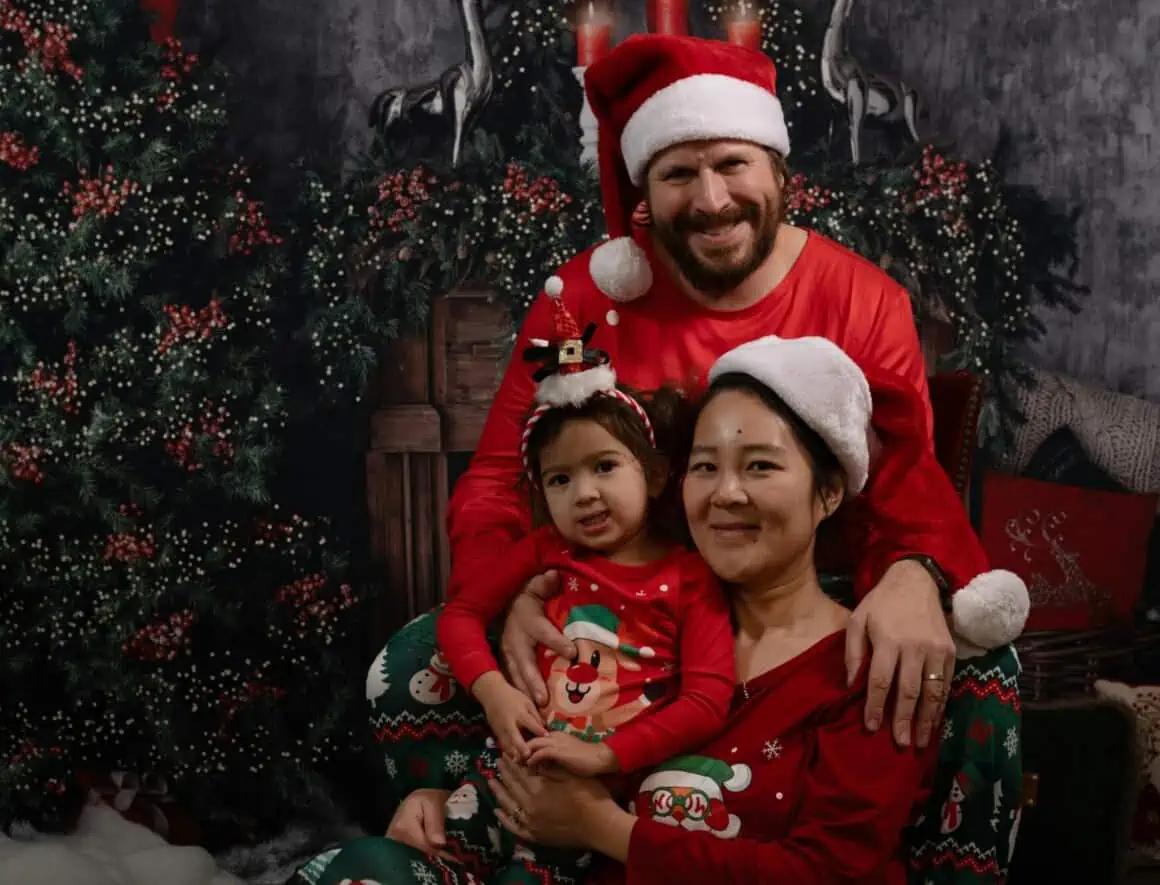 Happy family celebrating Christmas with Santa hats and festive outfits.