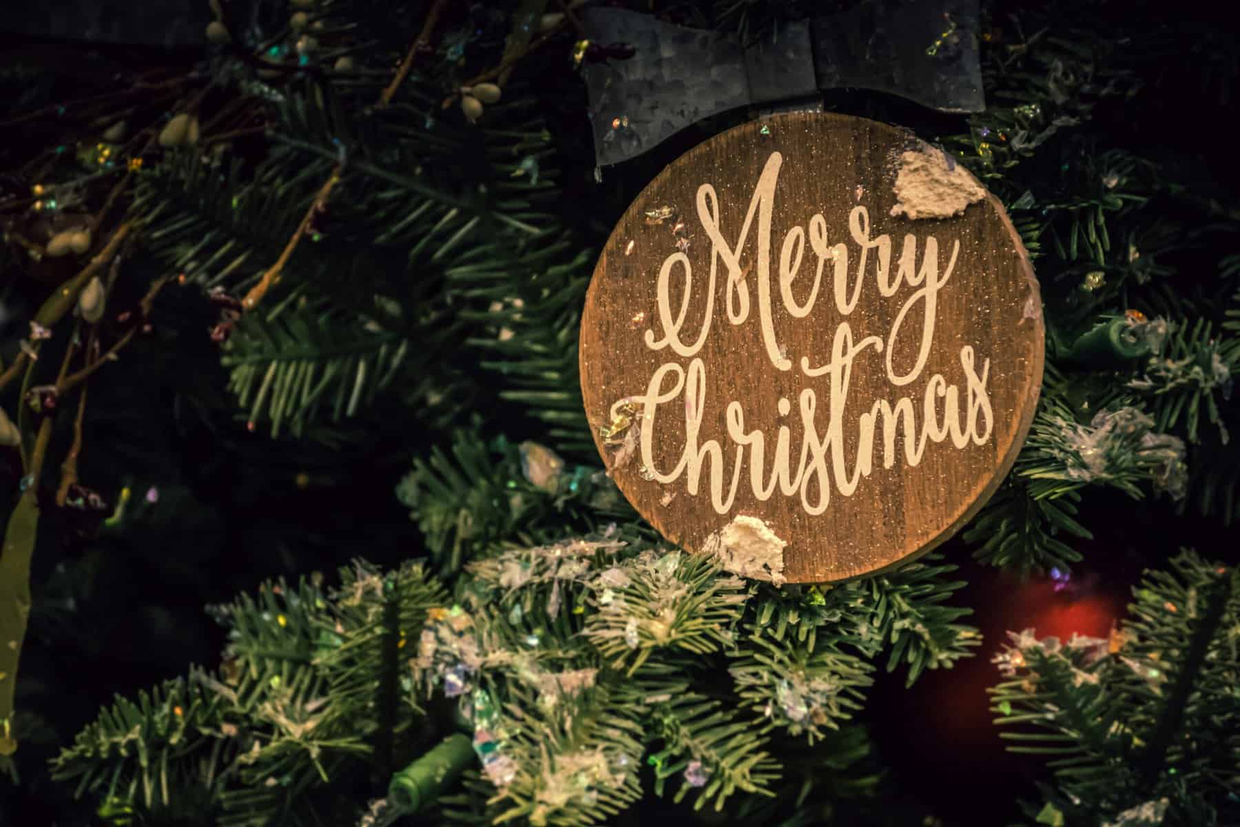 Merry Christmas sign hanging on a decorated Christmas tree.
