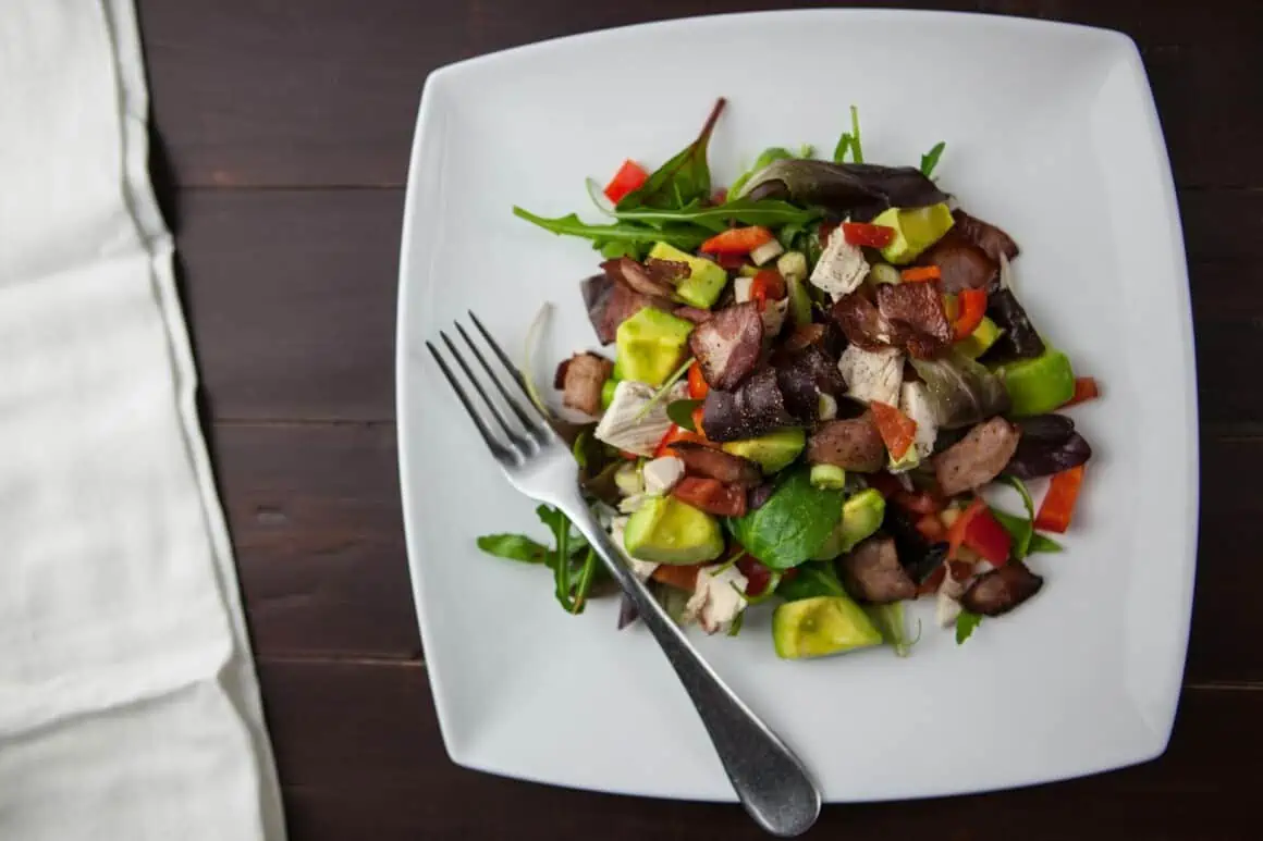 Fresh beef salad with vegetables on a white plate, healthy meal option.