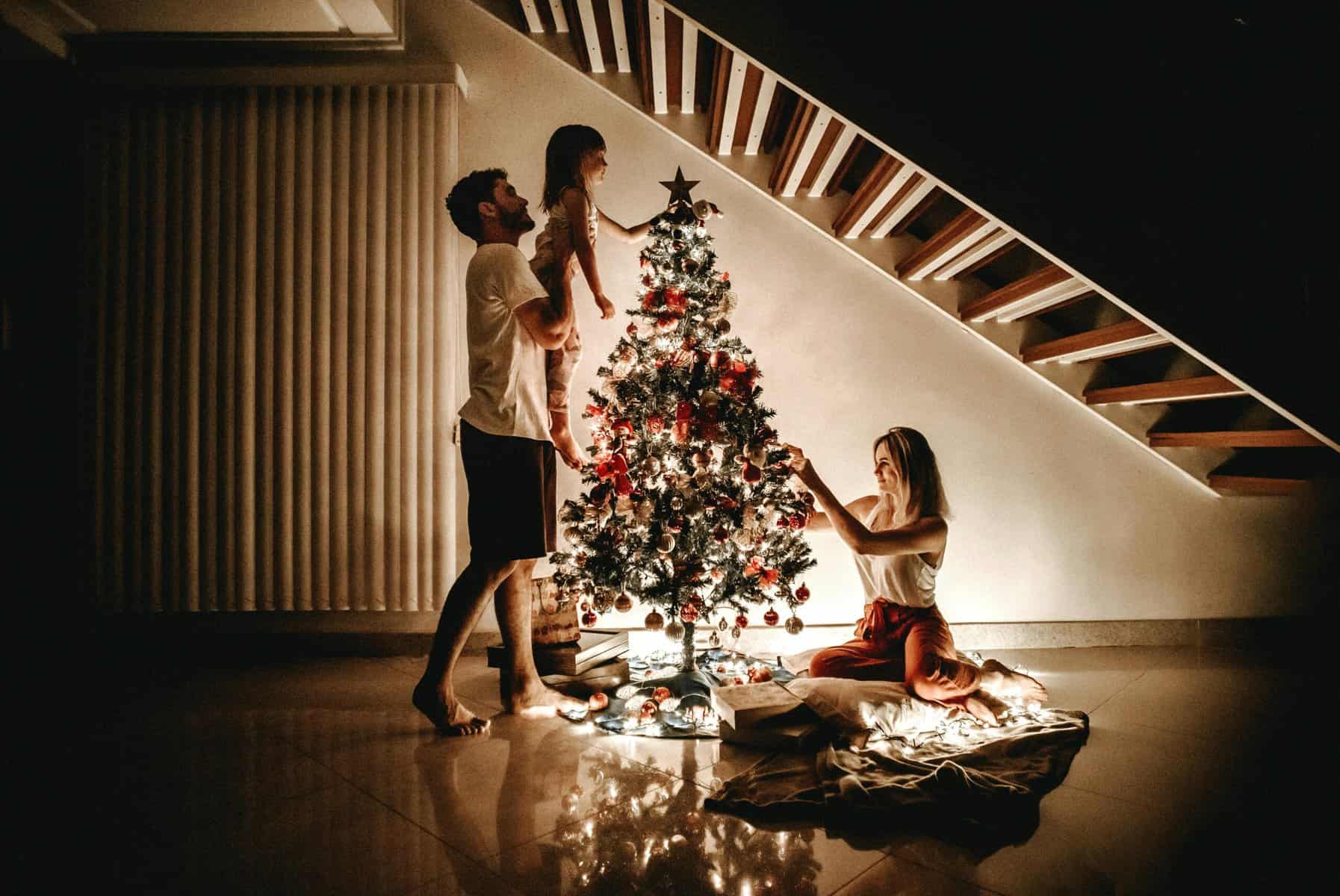 Family decorating a Christmas tree together at home.