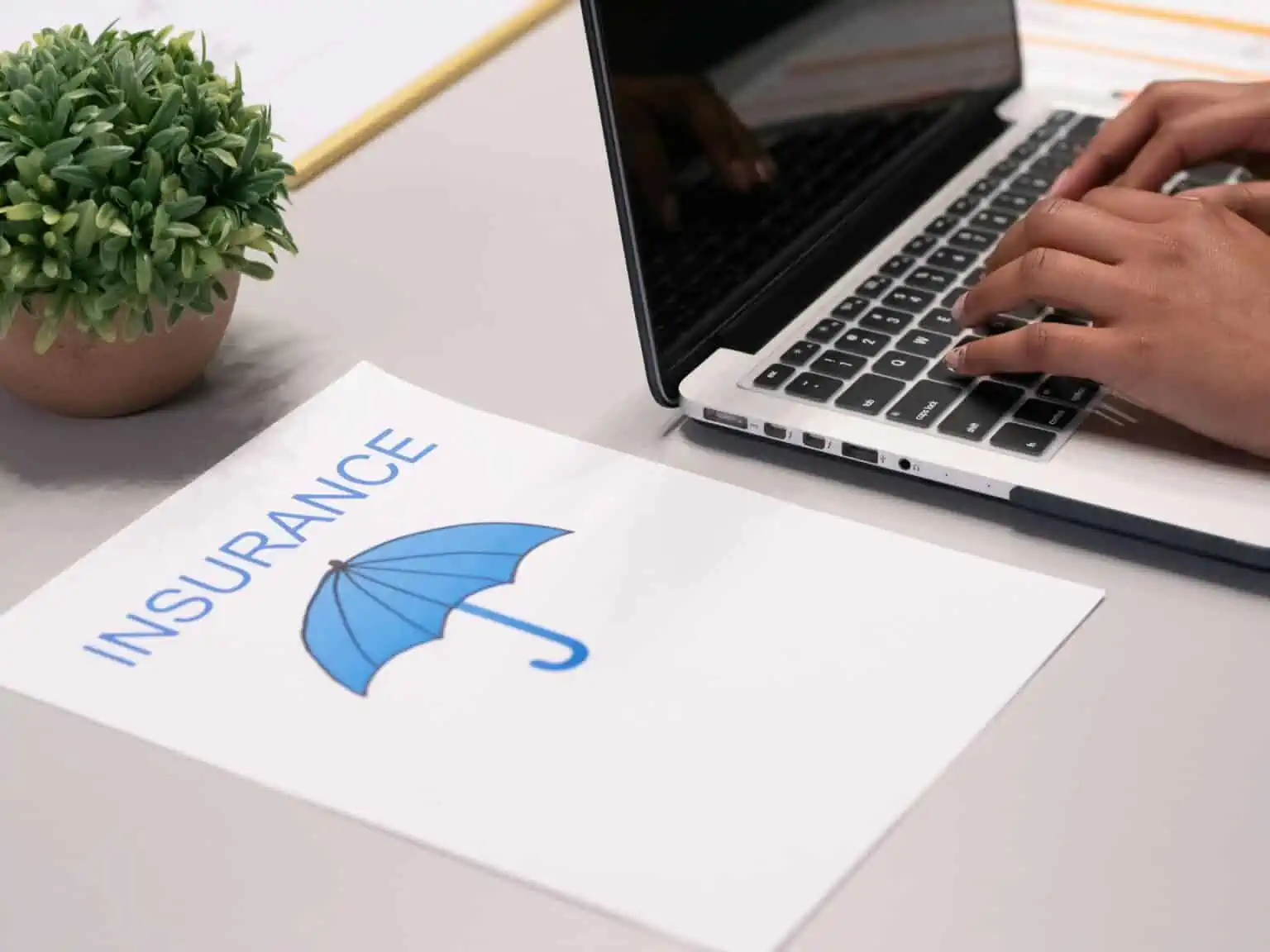 Insurance planning with a laptop and a document featuring an umbrella icon.