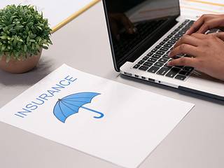 Insurance planning with a laptop and a document featuring an umbrella icon.