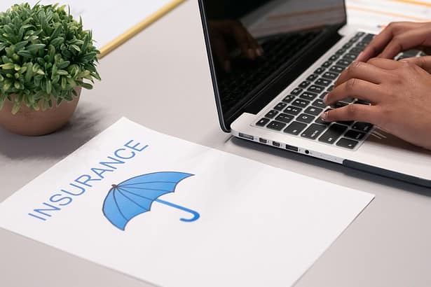 Insurance planning with a laptop and a document featuring an umbrella icon.