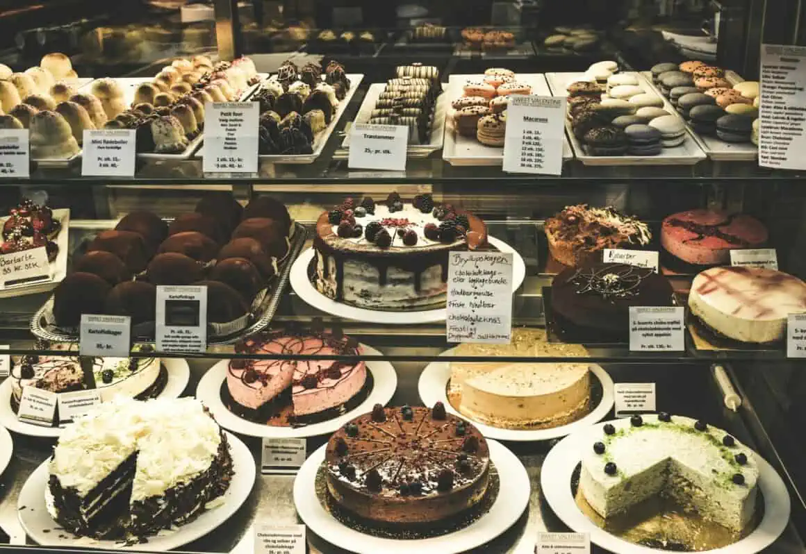 Delicious variety of cakes showcased in a bakery display case, including chocolate, fruit, and cream.