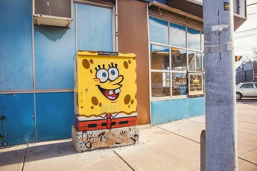 Colorful SpongeBob street art on utility box in urban setting.