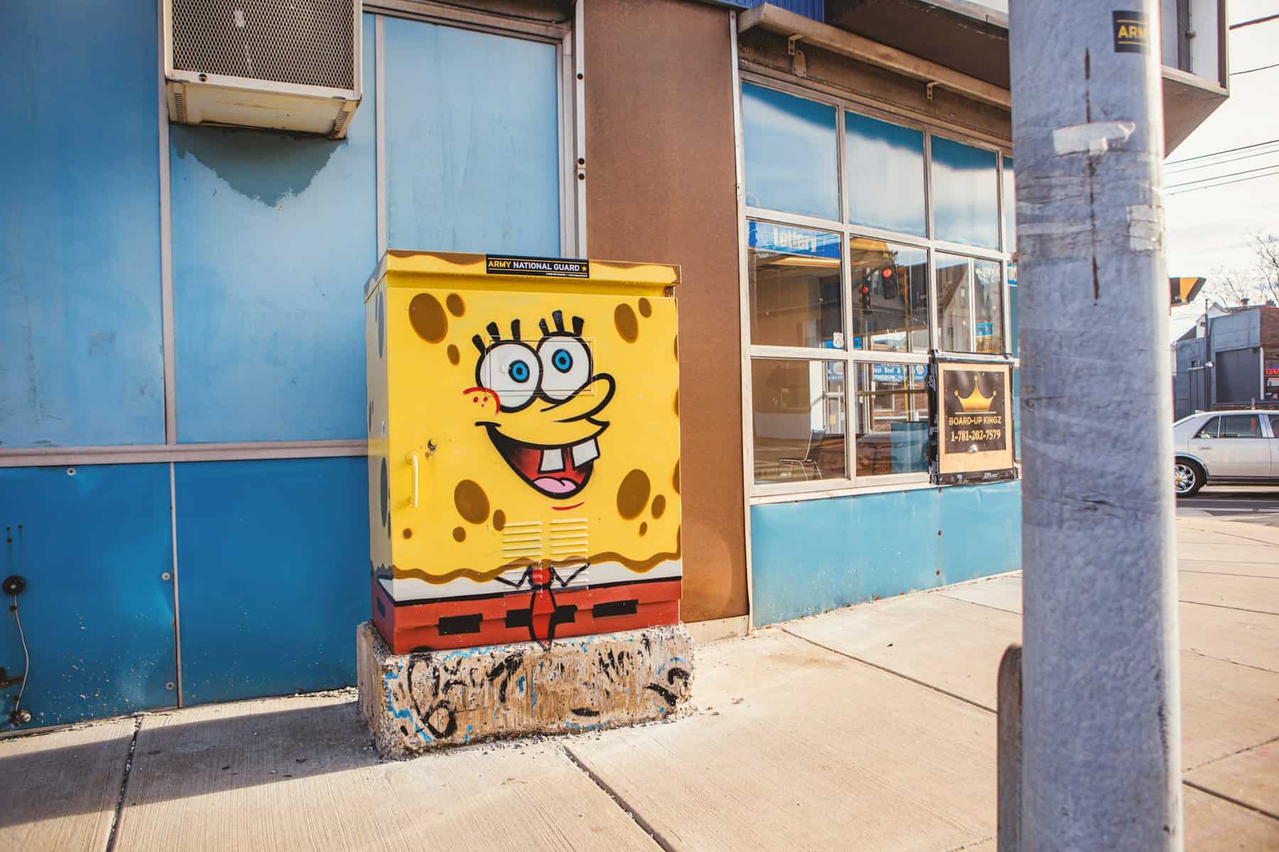 Colorful SpongeBob street art on utility box in urban setting.