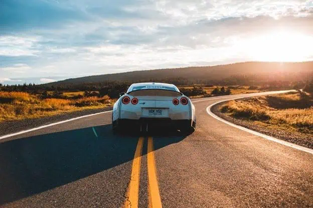 Understanding Car Insurance Costs: An Overview 1 Sports car driving on a scenic open road at sunset.