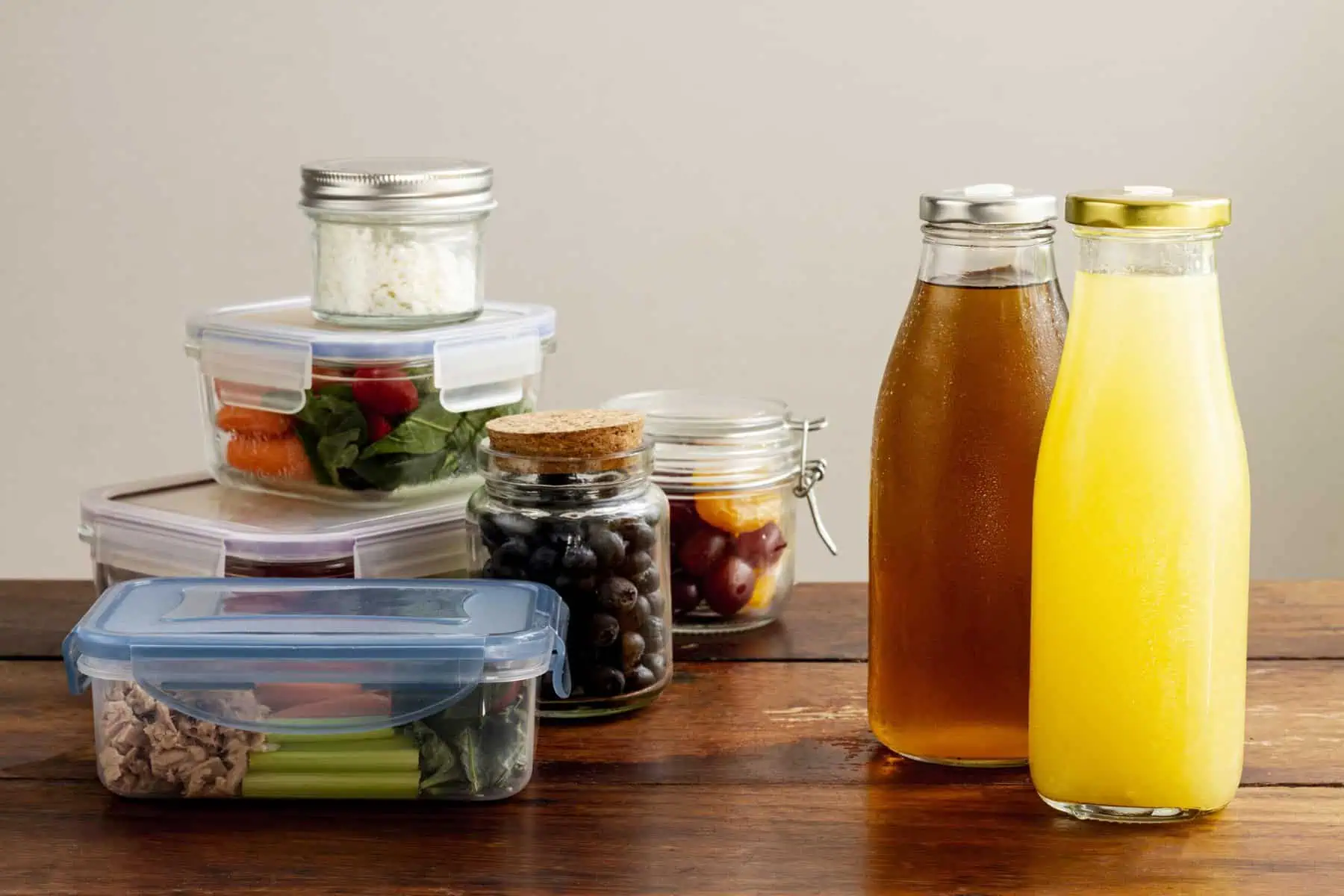 Preserved foods and drinks stored in glass jars and bottles on a wooden surface.