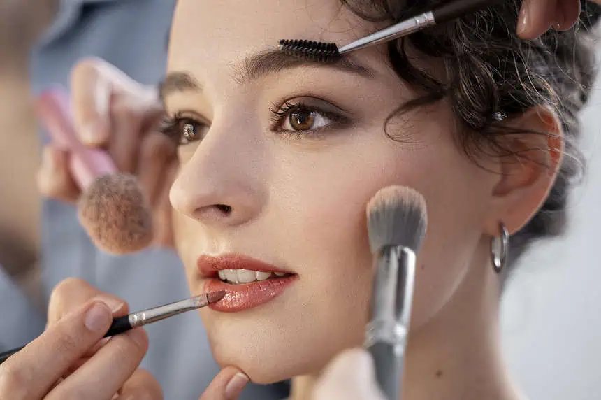 Makeup artist applying foundation and eye makeup to a young woman.
