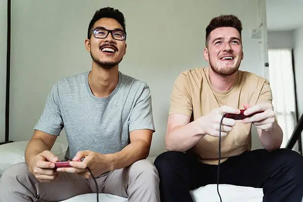 Two young men enjoying gaming session with controllers in hand.