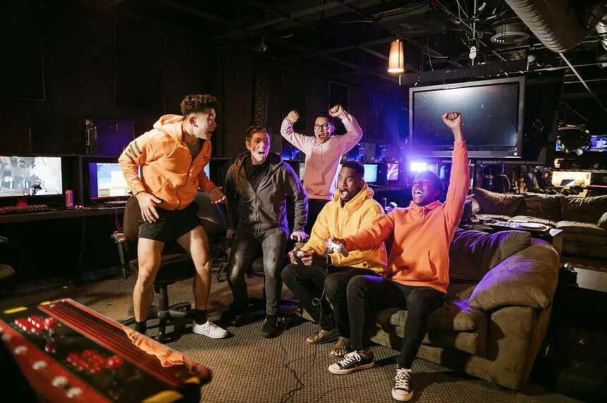 Gamer Friends are Legit Magic! But how to Make Friends through Gaming? 1 Friends enjoying a gaming session with excitement and victory gestures.