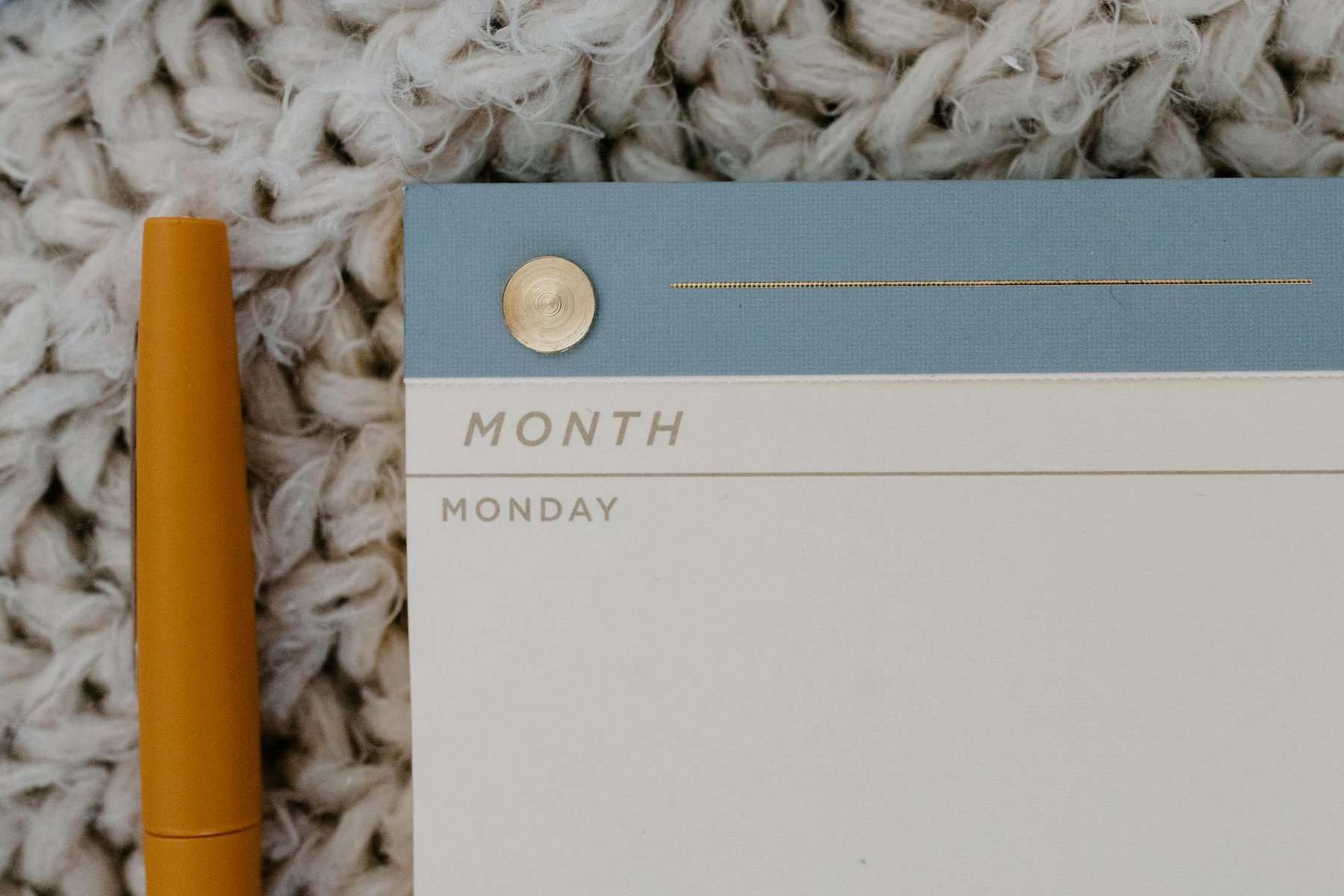 Monthly planner page with a yellow pen on a textured beige background.
