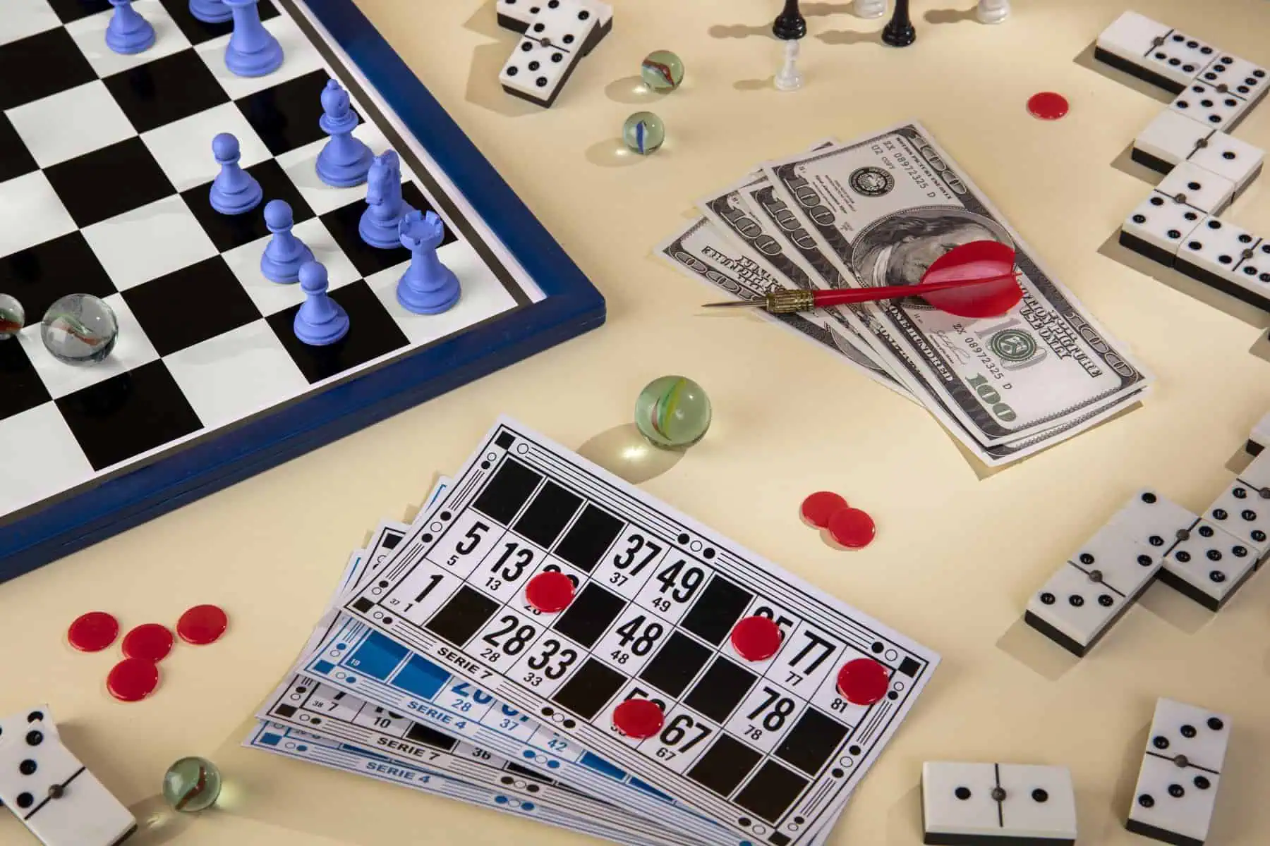 Chess and bingo game setup with money, dice, and game pieces on a table.