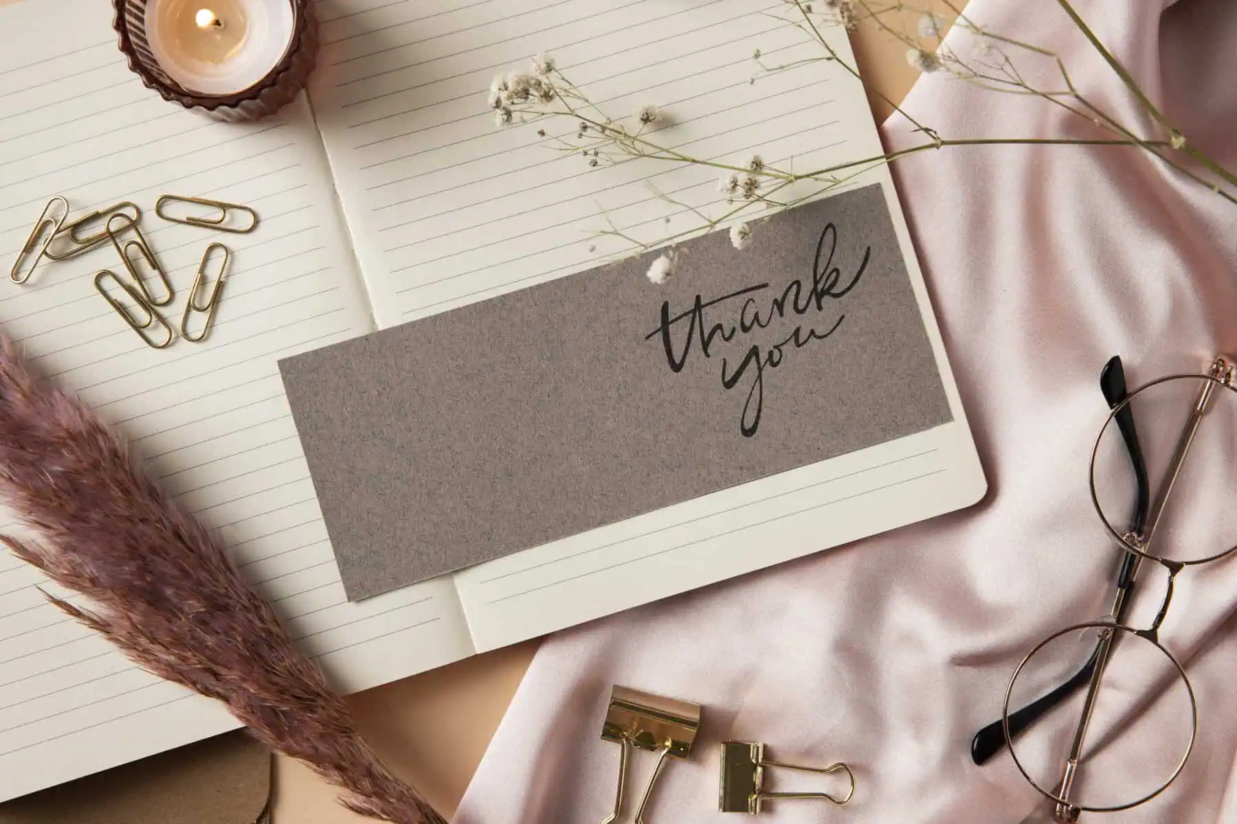 Elegant thank you card with stationery and dried flowers for gratitude message.