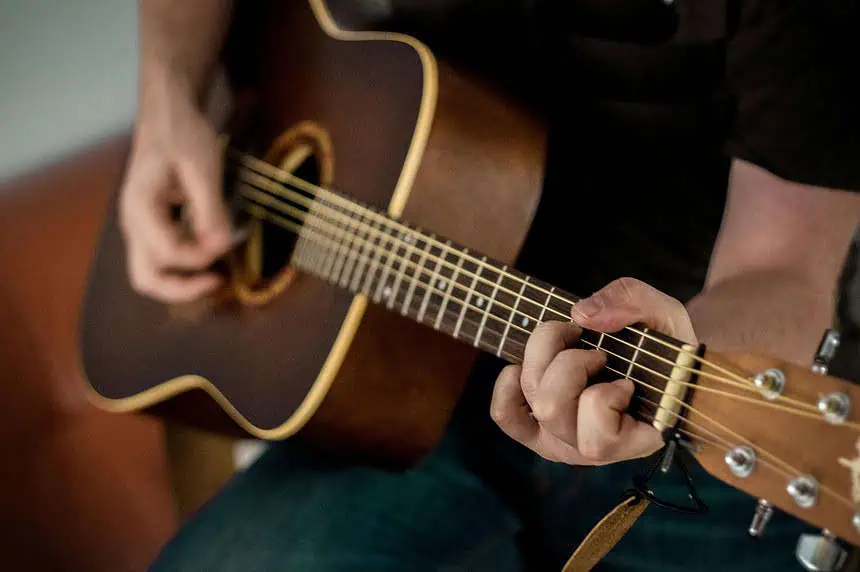 Close-up of a person playing an acoustic guitar with focus on hands.