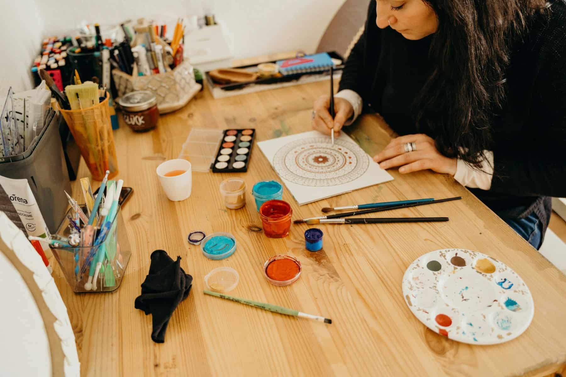 Home Icy 39 Woman painting intricate mandala design with watercolor paints.