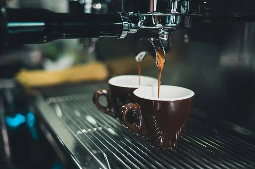 Coffee brewing process with espresso machine pouring into cups.