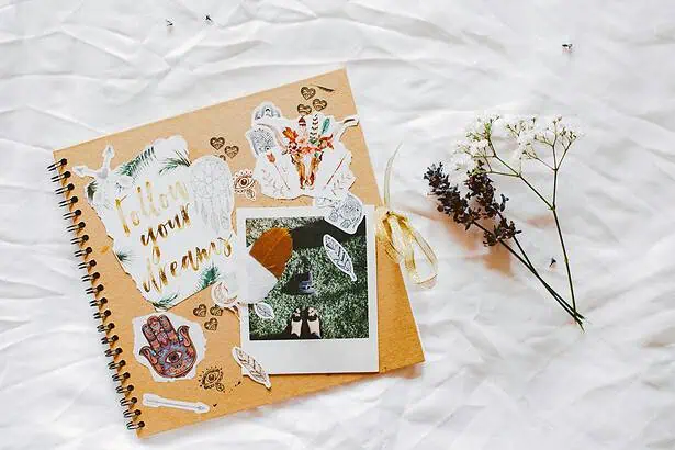 Scrapbook with floral decorations, heartfelt messages, and personal photos on a white textured backg.
