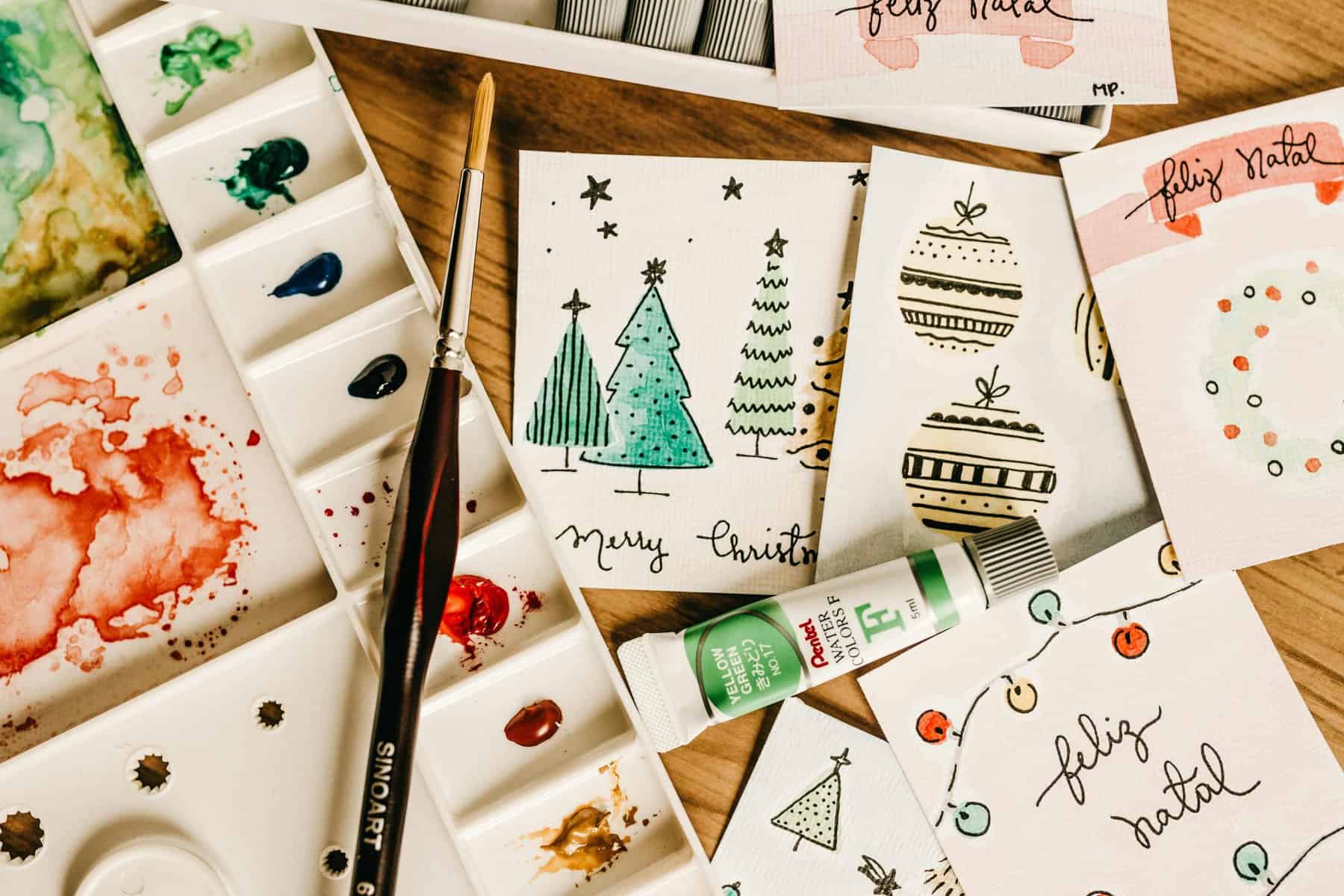 Creative Christmas card designs with watercolor paints and brushes.
