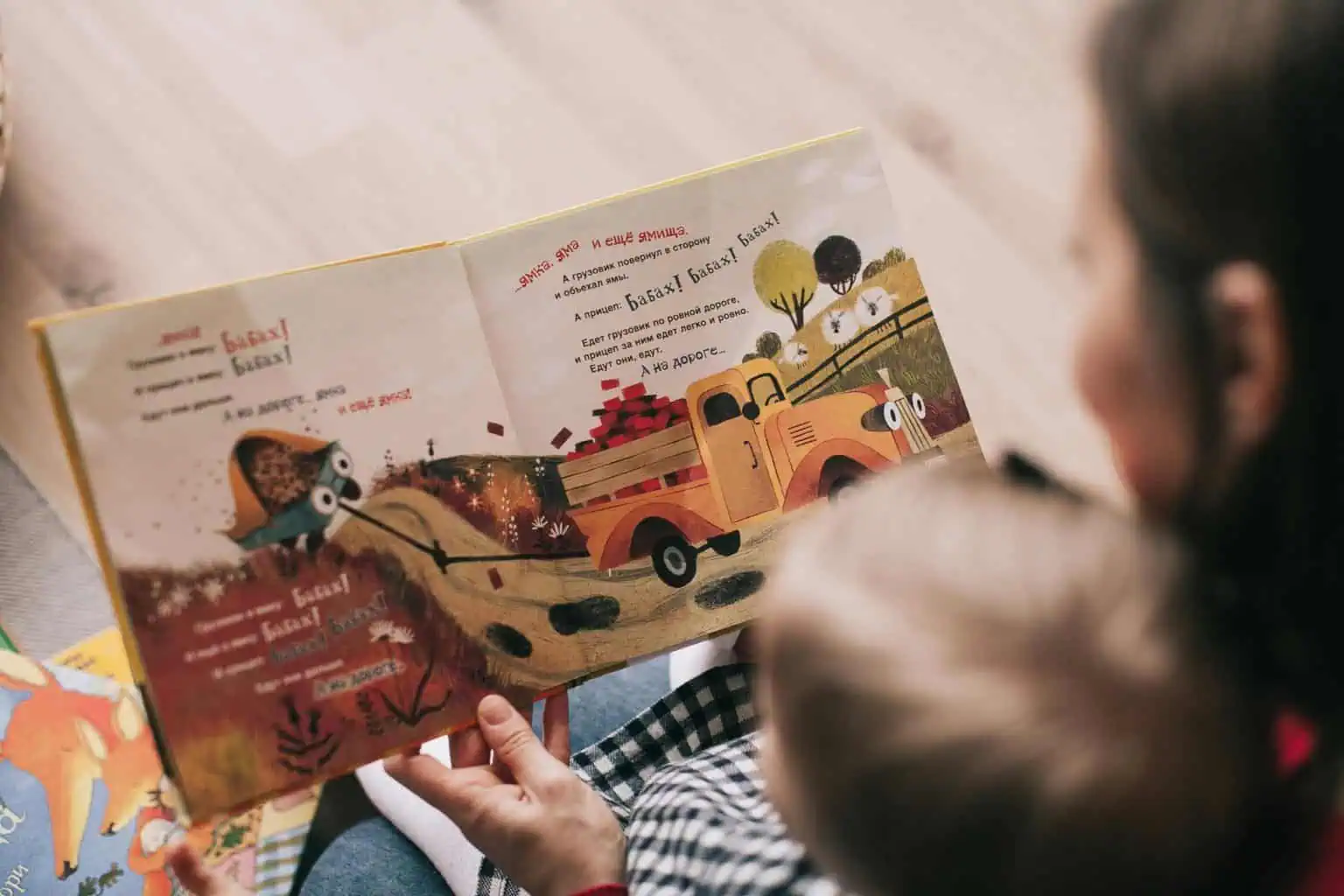 Children reading a storybook with vibrant illustrations of a truck and animals.
