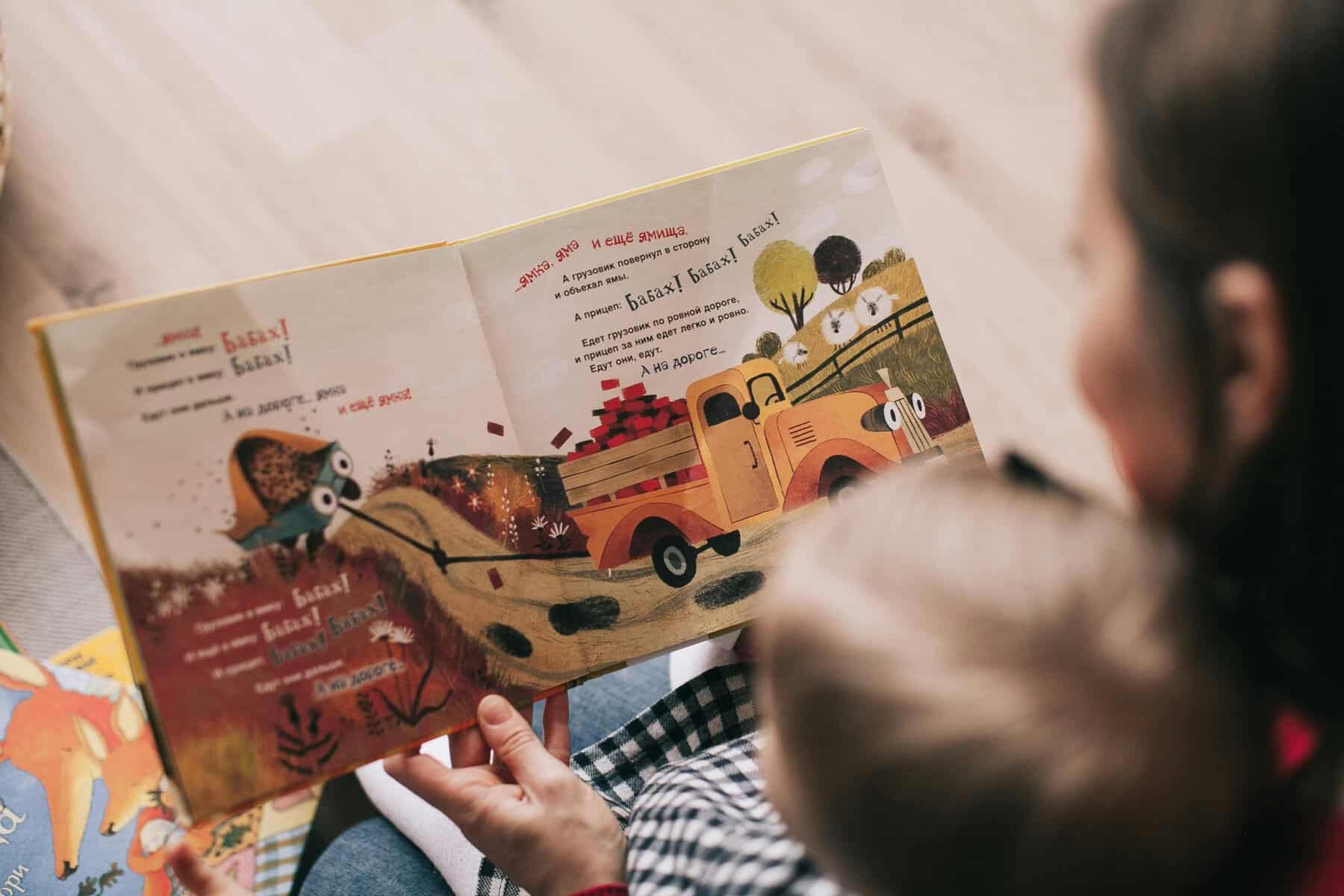 Home Icy 45 Children reading a storybook with vibrant illustrations of a truck and animals.