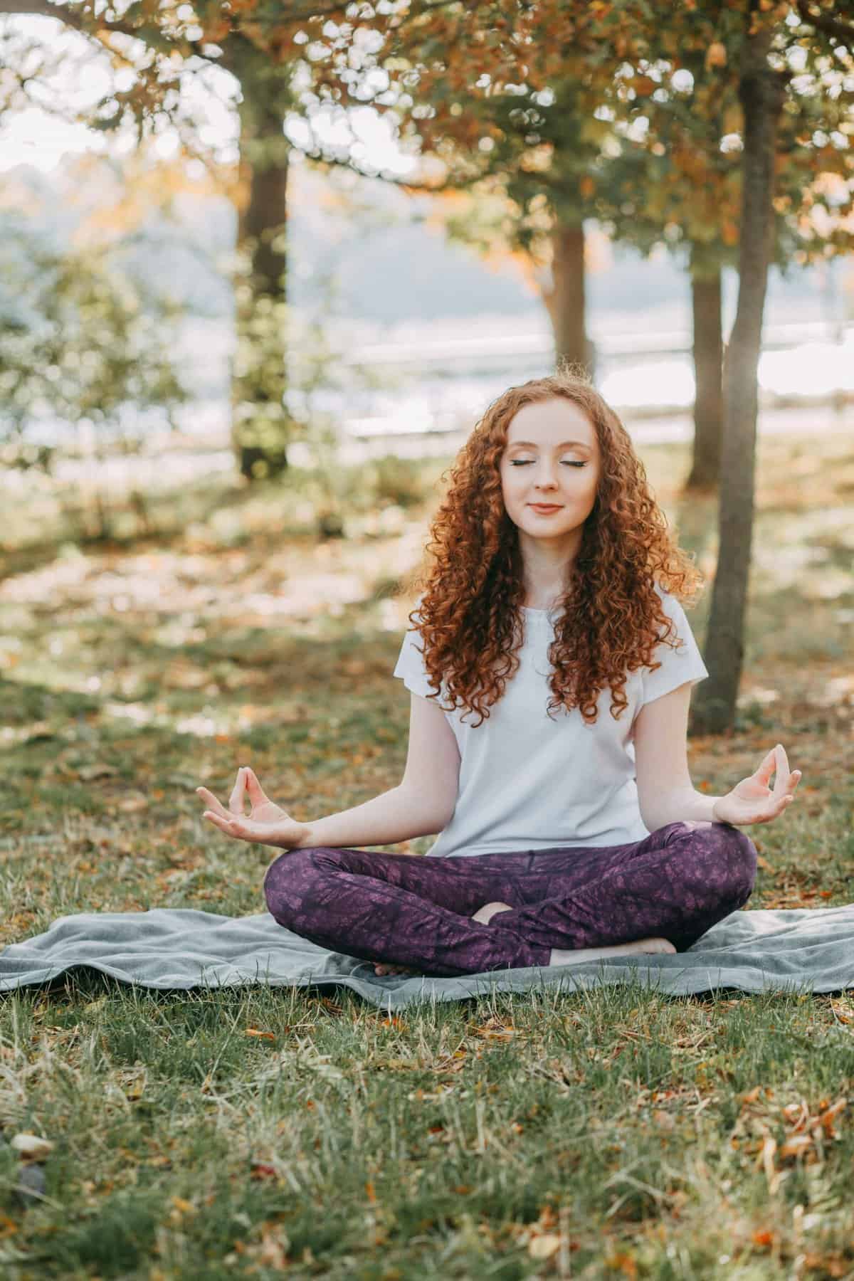 Peaceful woman meditating outdoors in park during autumn.