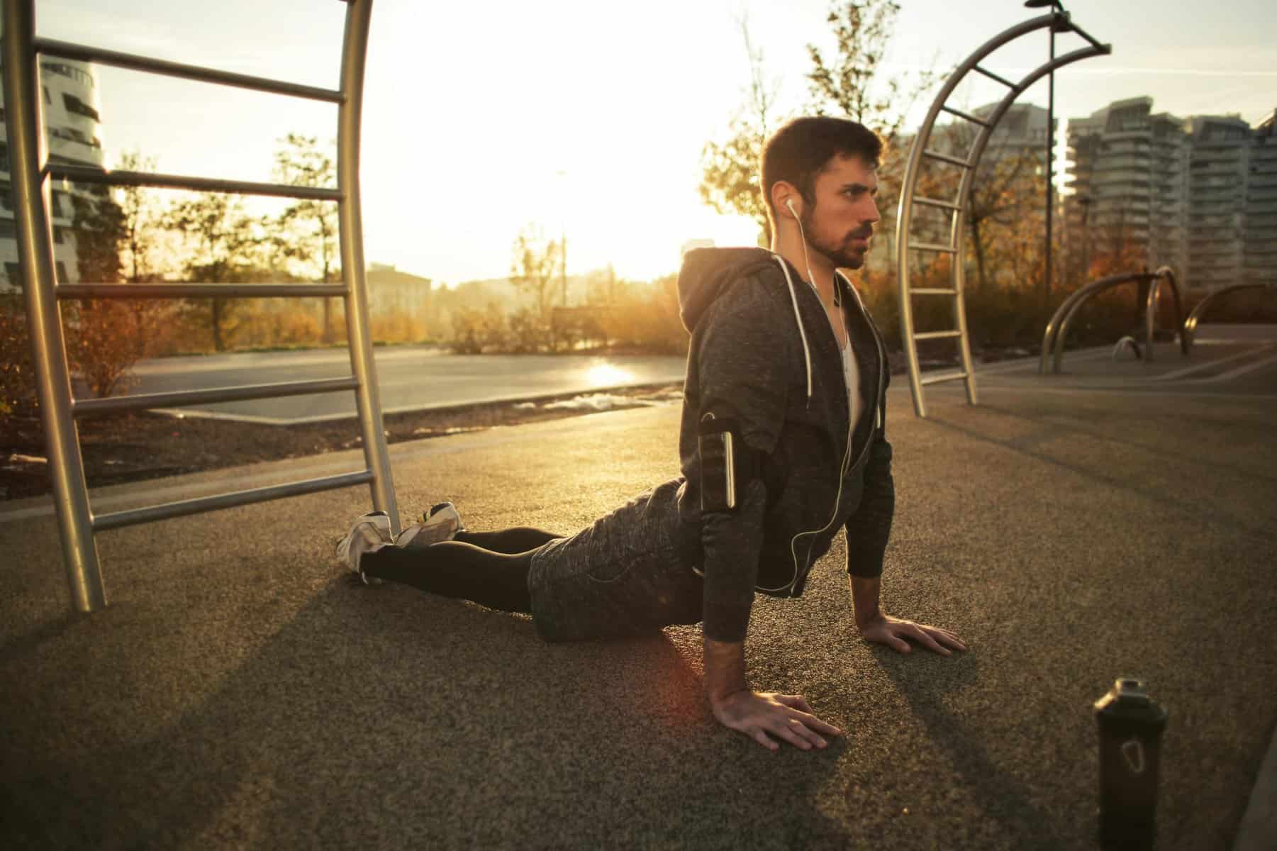 Man performing yoga stretch outdoors during sunset for flexibility and fitness.