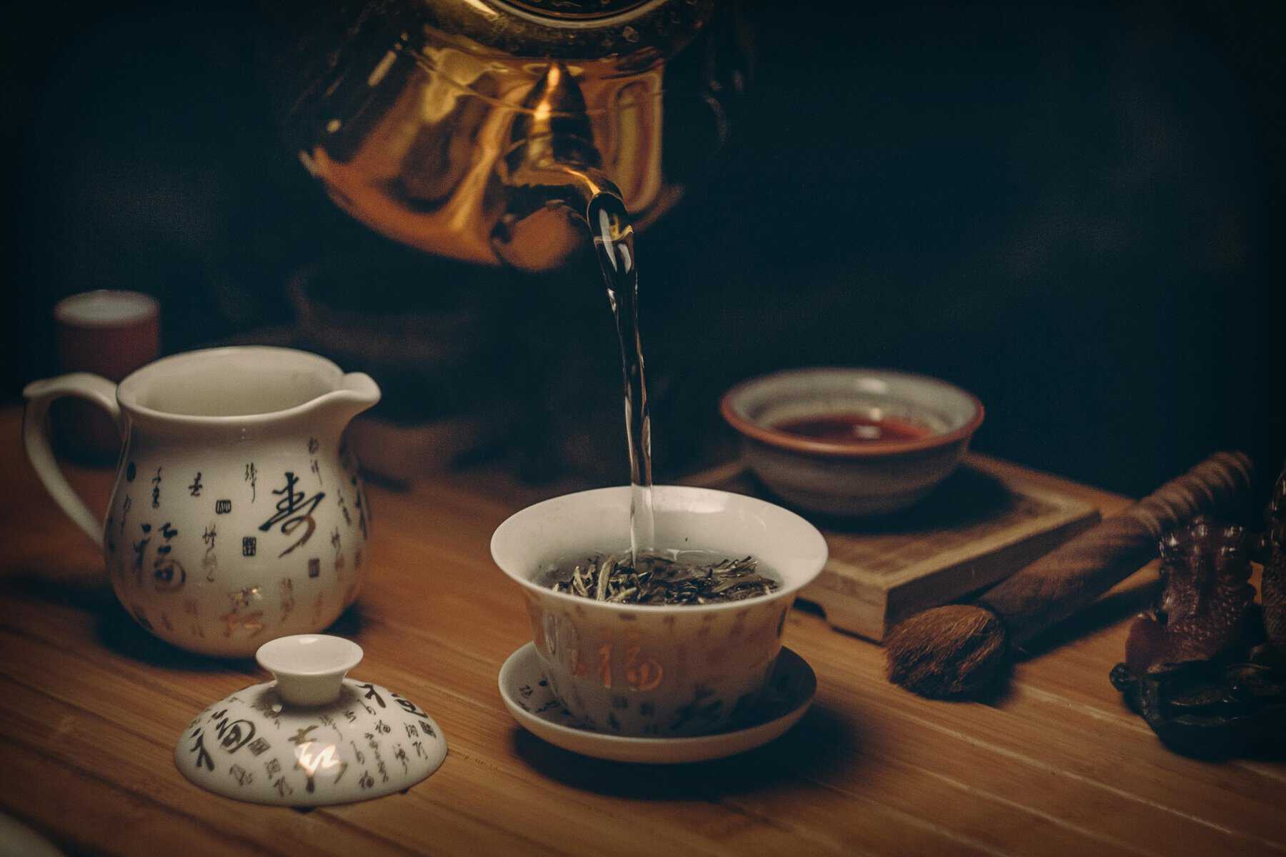 Home Icy 41 Tea pouring into a traditional Chinese teacup with tea set and accessories on a wooden table.