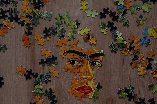 Artistic mosaic puzzle of a woman's face with colorful pieces on wooden background.
