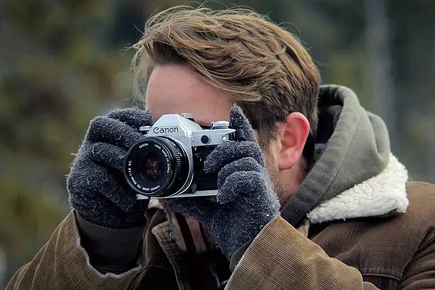 Photographer taking a photo outdoors with a Canon camera in a natural setting.