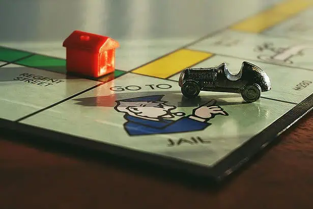 Board game with house and car pieces on Monopoly board.