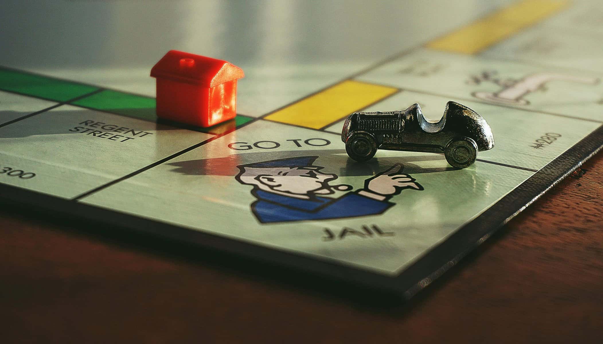 Board game with house and car pieces on Monopoly board.