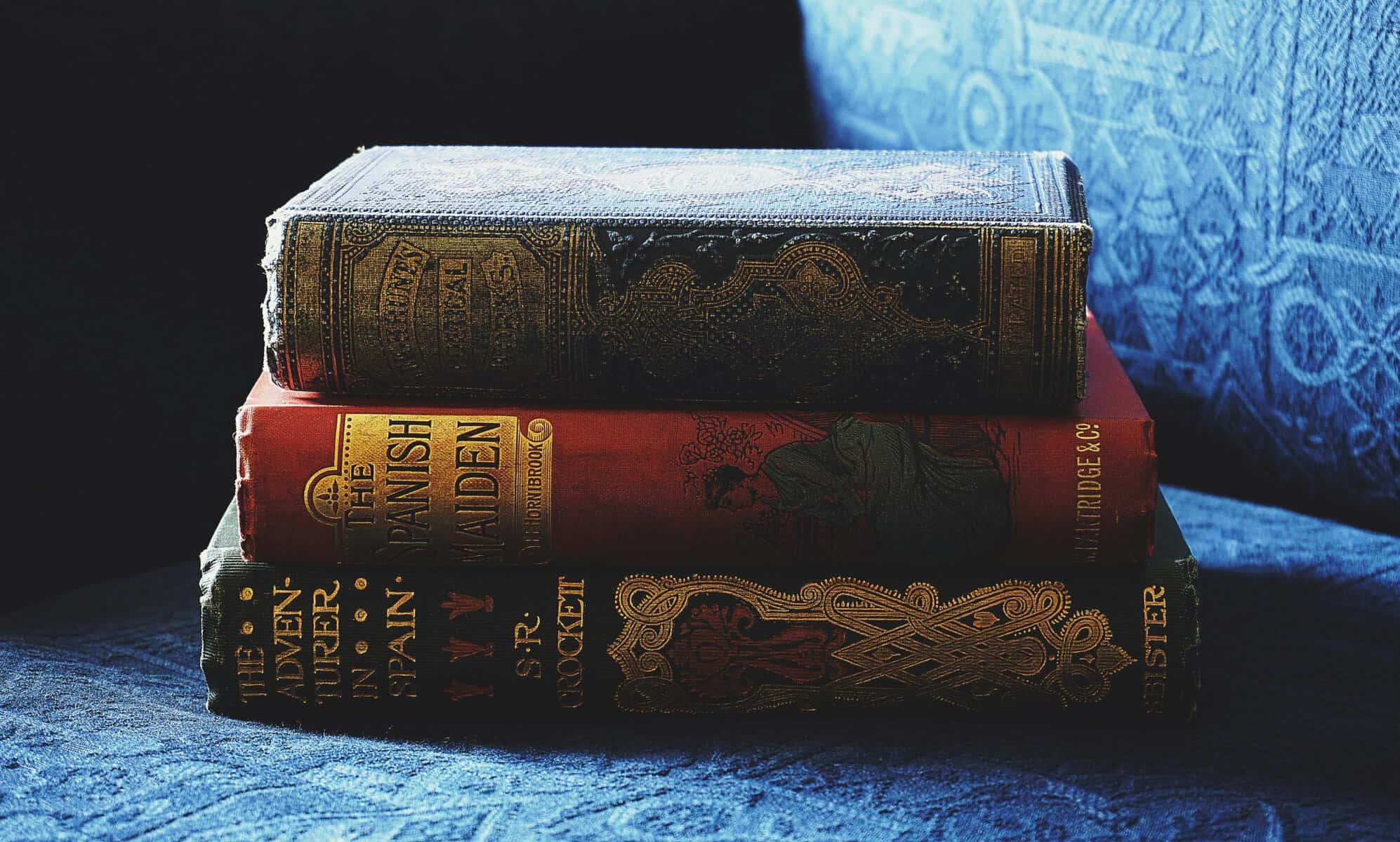 Old hardcover books with ornate designs and worn covers.