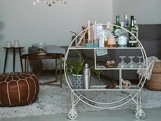 Stylish bar cart featuring bottles, glasses, and bar accessories in a modern living room setting.