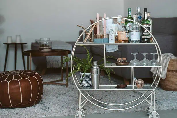 Stylish bar cart featuring bottles, glasses, and bar accessories in a modern living room setting.