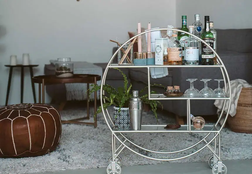 Stylish bar cart featuring bottles, glasses, and bar accessories in a modern living room setting.