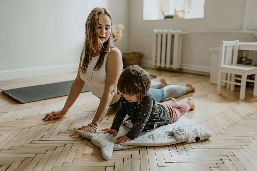 Mother and young child practicing yoga together on a mat indoors.