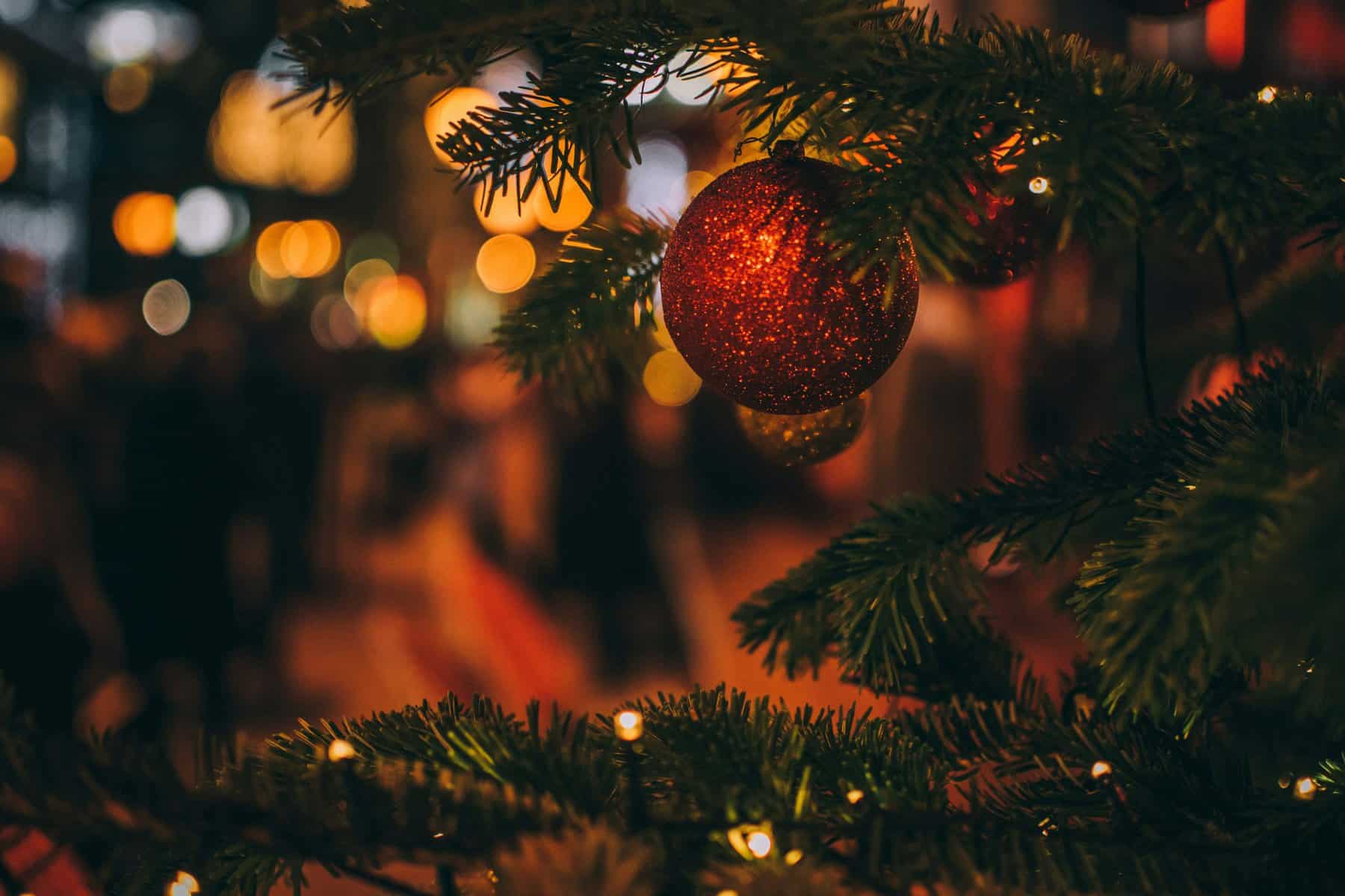 Christmas tree ornament hanging on a decorated Christmas tree with blurred festive lights in the bac.