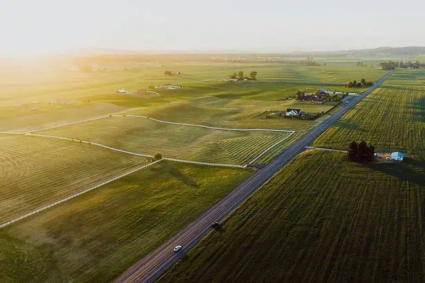 Farm landscape at sunset with fields and a road, rural scenery.
