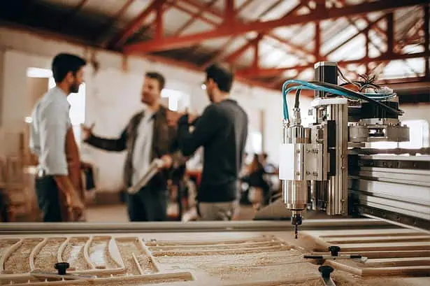 CNC machine operating in a manufacturing plant with workers discussing production processes.