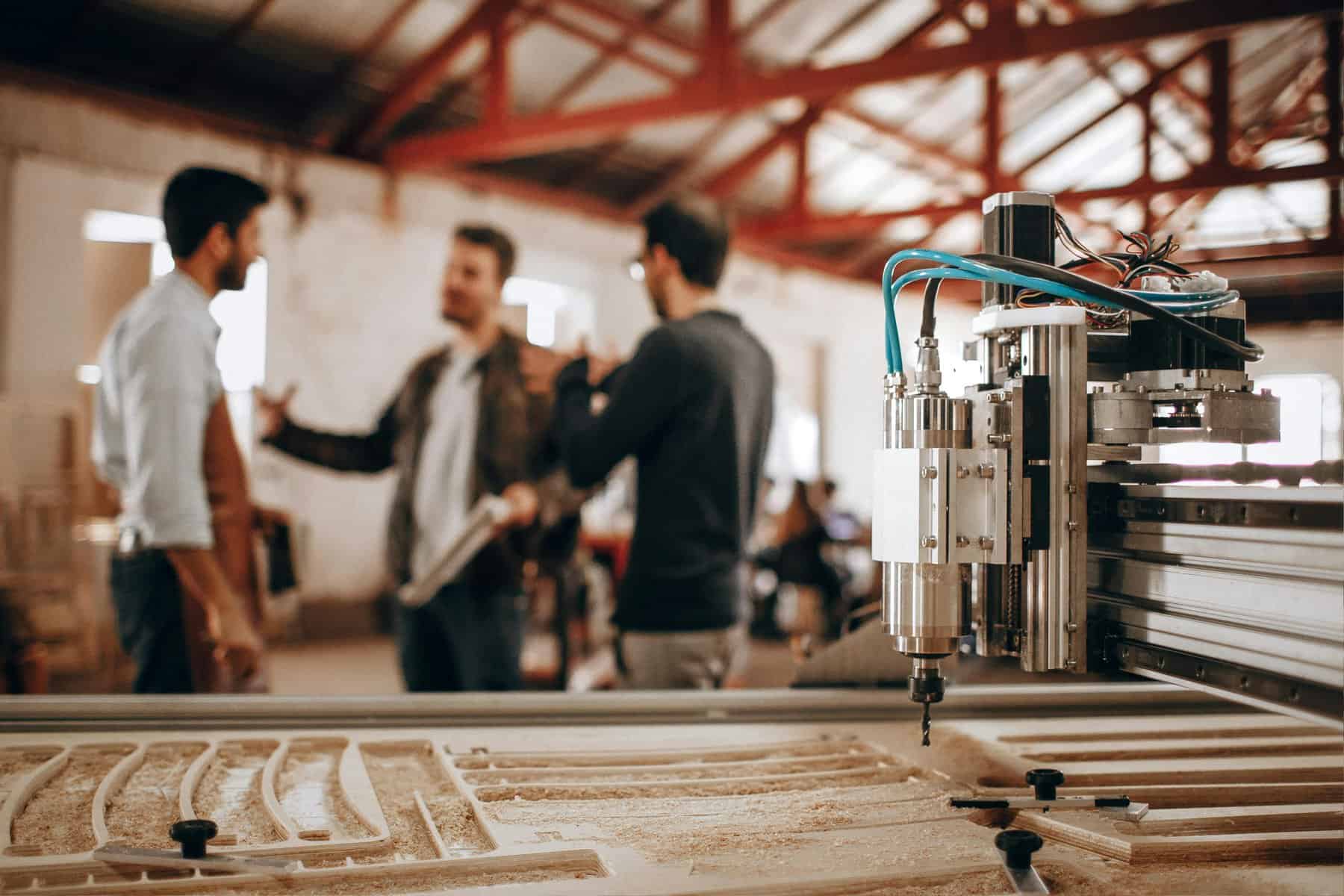 Home Icy 44 CNC machine operating in a manufacturing plant with workers discussing production processes.