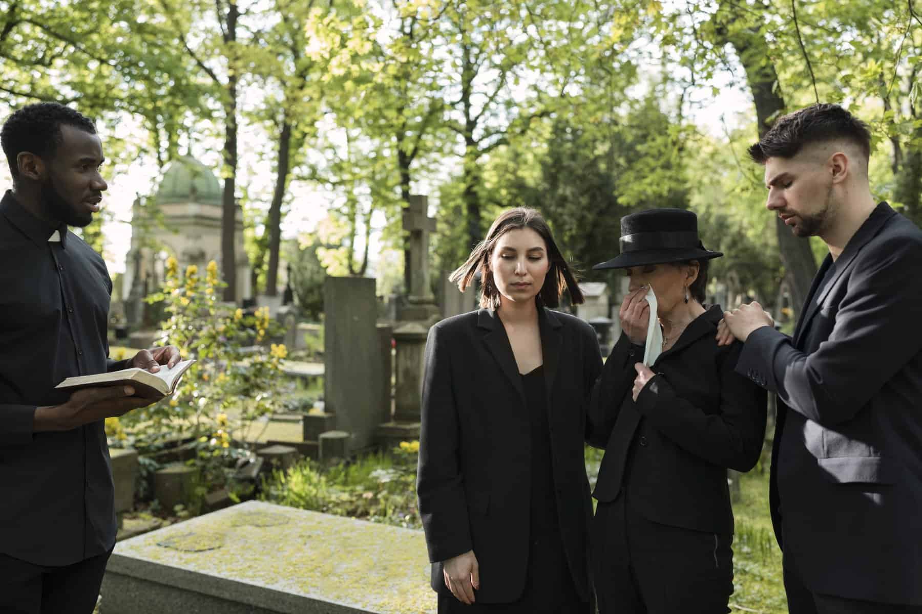 Group of people mourning at a cemetery during a funeral service.