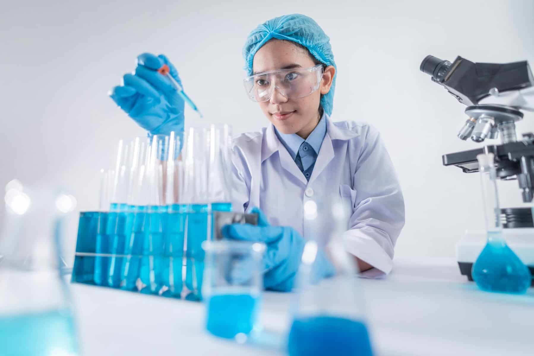 Scientist in lab with test tubes and blue liquids, performing scientific research.