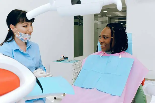 Dental checkup with dentist and patient in clinic, smiling during examination.