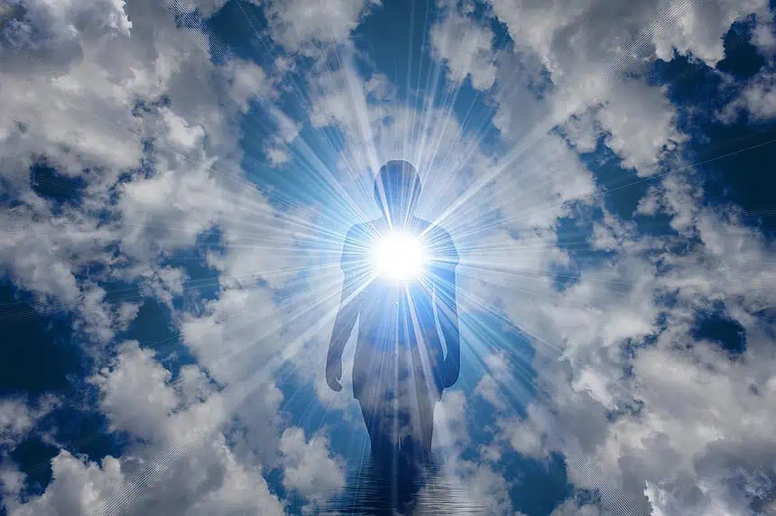 Sunlit silhouette of a person standing against a bright sun and dramatic clouds in the sky.